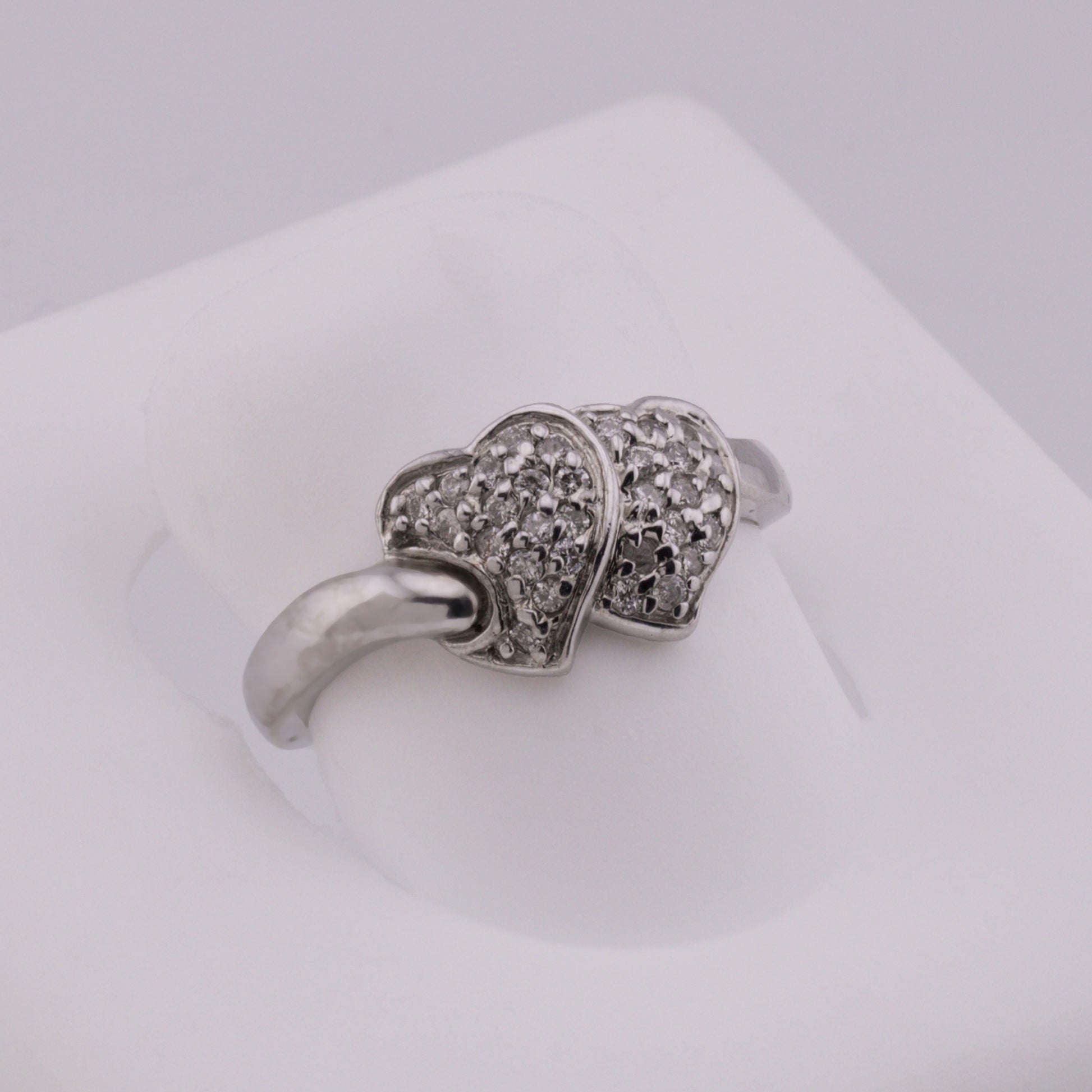 Silver ring with diamond accents on a light gray background
